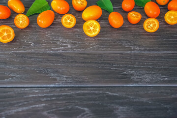 ripe kumquat fruit on a wooden background. kumquat and kumquat halves on the table.