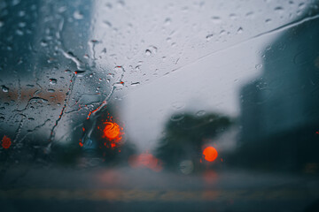 Close up of windshield in heavy rain with bokeh of traffic light