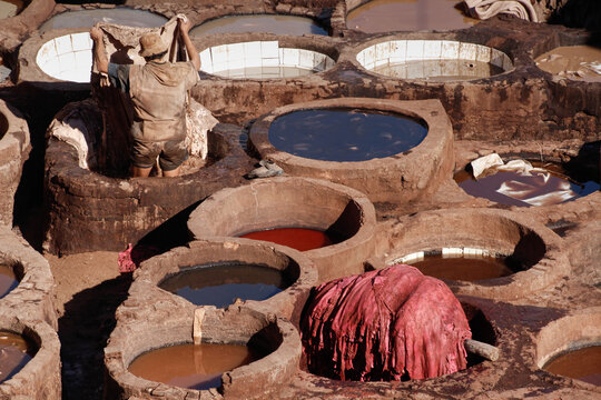 Leather dying in a traditional tanneries, Medina of Fez, Morocco. with stone vessels filled with colored dyes (Chouara Tannery). A popular tourist destination in Morrocco, North Africa.