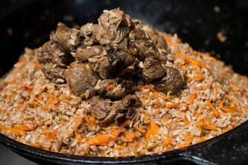 Step-by-step process and stages of cooking oriental cuisine - pilaf. Hot fresh pilaf in a cauldron