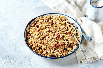 Homemade granola with berries and nuts in a bowl on a gray background