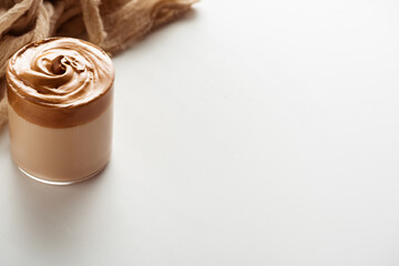 delicious Dalgona coffee in glass near cloth on white background