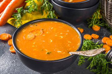 Delicious homemade cream carrot soup. Vegetable carrot soup puree on dark gray table with fresh carrots copy space