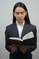 Young Asian businessman with long hair reading book