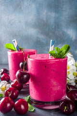 Sweet cherry smoothie drink in glass jars with mint leaves and fresh berries