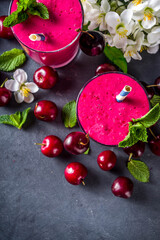 Sweet cherry smoothie drink in glass jars with mint leaves and fresh berries