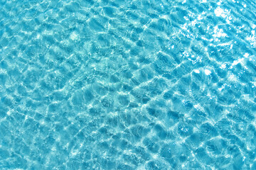 Background shot of aqua water surface. Swimming pool with sunny reflections.