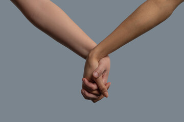 Close-up of light-skinned and dark-skinned people holding hands