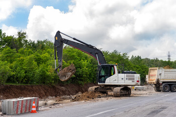 Many heavy heavy industrial road construction machinery on new highway road construction site sunny day with blue sky background. Tipper dumper truckand excavator machine building freeway