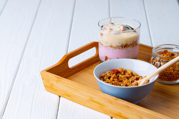 Tasty breakfast with granola, yoghurt and fruits in a glass bowl