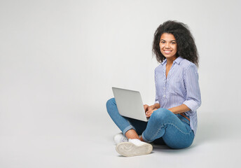Naklejka premium Portrait of a beautiful african woman with laptop on grey background