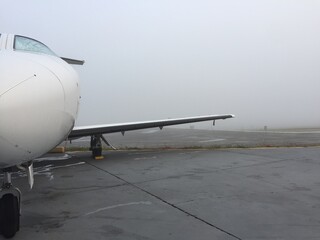 Foggy business jet parked at airport with heavy fog around