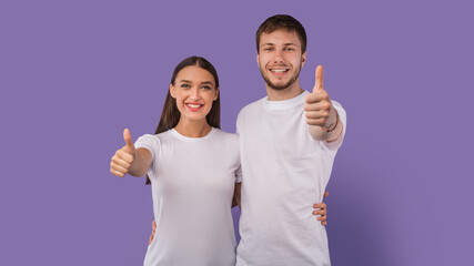 Happy couple showing thumbs up and smiling at studio