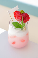 strawberry cocktail in front of a white background. cold pink cocktail with ice on the beach club in hot summer day. cocktail image with foam on the background with sun beds and towels