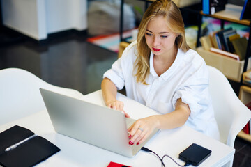 Prosperous attractive business woman checking financial reports installing application on laptop...