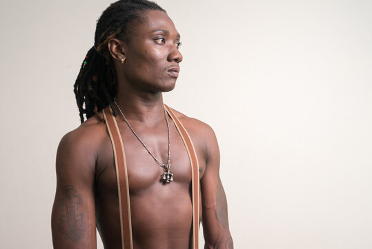Young handsome muscular African man with dreadlocks thinking shirtless