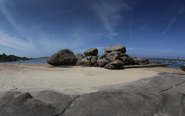 Boats on a sunny day in the bay of the sandy beach of Coz-Porz with large granite boulders on the English Channel in Tregastel (Brittany, France)