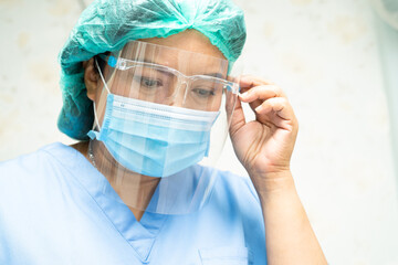 Asian doctor wearing face shield and PPE suit to check patient protect safety infection Covid-19...