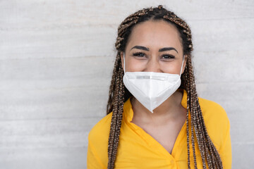 Young woman with braids smiling in front of the camera while wearing face mask during coronavirus...