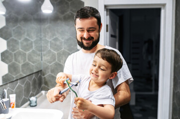 Father and son have a fun while brush teeth together, they toothbrushes fight