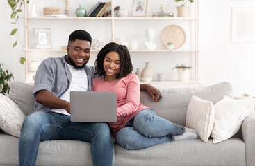 Weekend Passtime. Married Afro Couple Using Laptop At Home Together, Watching Movies