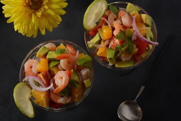 Ceviche salad with shrimps, oranges and avocado in glass bowl on a dark or grey background. Latin American food. Delicious, freshly made shrimp ceviche. Shrimp marinated in lime and orange .