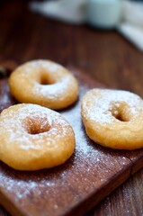 Three powdered sugar donuts on rustic table for snack food or breakfast.