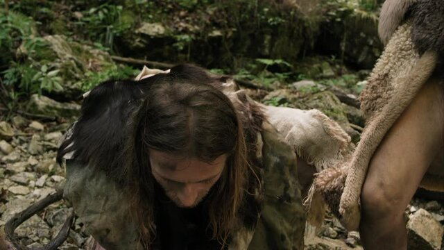 Man Looks Up Thankfully At Sky Before Washing Face In Stream As Friend Stands By