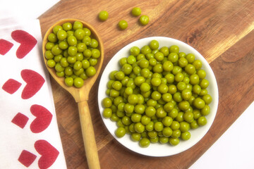 Marinated green peas. Peas. Canned green peas in plate. Green peas in a wooden spoon macro shot.  Зеленый горошек. 