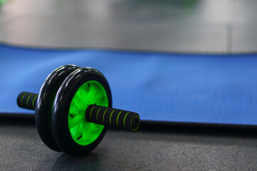 Obraz na płótnie Canvas Press roll on the floor near the mat in the fitness room. The development of abdominal muscles with a roller, a prepared place for training the press.