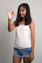 Portrait of young beautiful Asian teenage girl showing ok sign