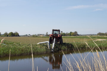 Pasture landscape in North Holland. With a tractor, water is pumped from a canal to the meadows....