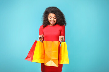 Portrait of a beautiful african woman with shopping bags on blue background