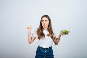 Fototapeta na wymiar girl in a white t-shirt holds a bowl of salad in her hands and eats on a white background. Healthy Eating