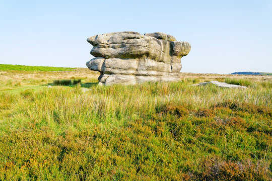 The Eagle Stone gritstone outcrop on Baslow Edge on a bright, hazy summer morning