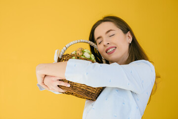 Happy Easter. Young woman hold Easter eggs on yellow background. Traditional spring holiday food, copy space