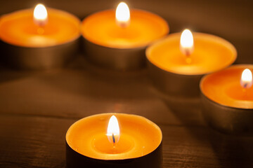 Obraz na płótnie Canvas Five burning orange aroma candles with wooden background macro
