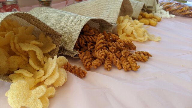 Snack table. Fried pasta, wheat, peanut and potato chips snacks inside brown bags.