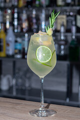 A refreshing summer cocktail with a slice of lime. Alcoholic drink. Garnished with a sprig of mint and ice cubes. In the bar.