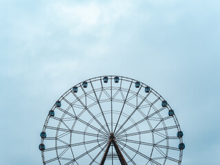 High modern ferris wheel with closed booths on a background of blue sky