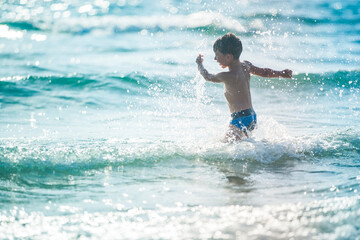 A little boy on the beach, playing with the waves © Olivia