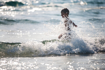 A little boy on the beach, playing with the waves