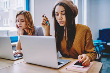 Concentrated african female freelancer watching important webinar on modern laptop computer while...