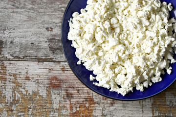 Selective focus. Freshly grained cottage cheese in a blue plate. Dairy products.