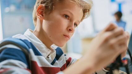 Portrait Shot of a Smart Schoolboy Constructs Small Robot for Robotics Engineering Class. Elementary School Science Classroom with Gifted Brilliant Children Working with Technology