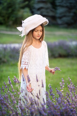 Beautiful girl with long hair at sunset in the park. Girl in the lavender field. The child walks in nature. Summer sunsets
