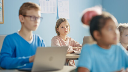 Elementary School Computer Science Class: Cute Girl Uses Digital Tablet Computer, Carefully Listening to a Teacher. Children Getting Modern Education in STEM, Playing and Learning.