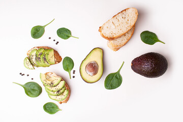 Bruschetta with avocado and baguette on a white table. Flat lay style