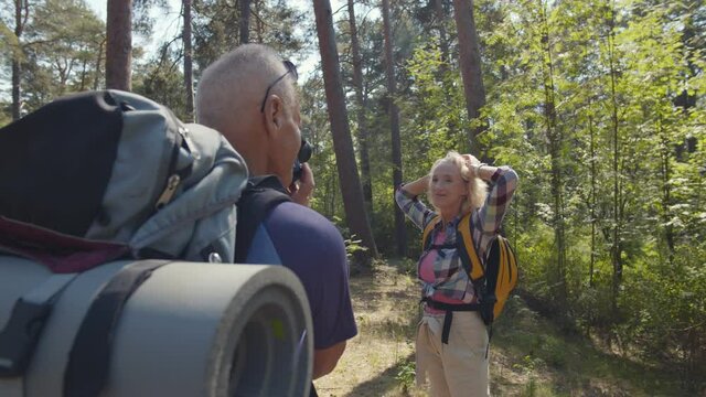 Senior man hiker taking photos of his wife during trip.