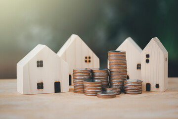 Money coin stack to show growing graph with wood house model,investment in the real estate business.Loans for purchase of residential houses.Save money and thinking plan for the future.